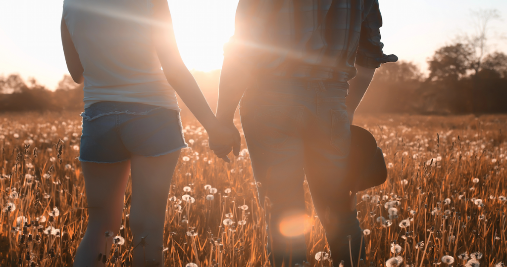 Pareja caminando de la mano al atardecer, imagen que representa la diferencia entre el amor sano y la dependencia emocional en una relación.
