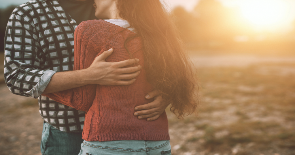 Pareja abrazándose al aire libre, imagen que representa el apego afectivo y la dependencia emocional en una relación de pareja.